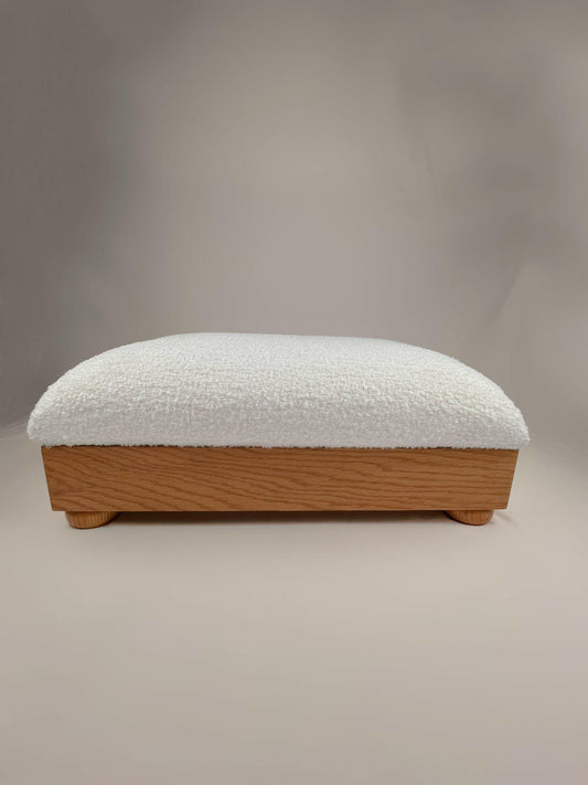 Earthly Cloud - msoth The Earthly Cloud rectangular footrest is an elegant and comfortable addition to any living space. It features a luxurious boucle upholstery in a soft, inviting cream color and a sturdy litEre wood frame supported by short, rounded legs. The frame has a natural finish, adding a touch of warmth and sophistication to any room. The footrest offers support and comfort for your feet, reducing fatigue and improving circulation. 